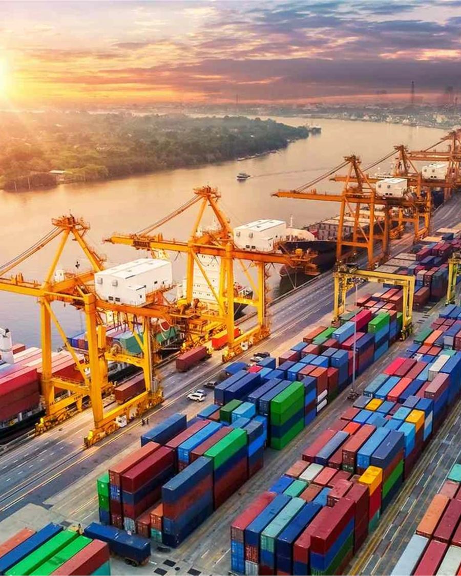 Aerial view of a busy container port with gantry cranes loading a cargo vessel.